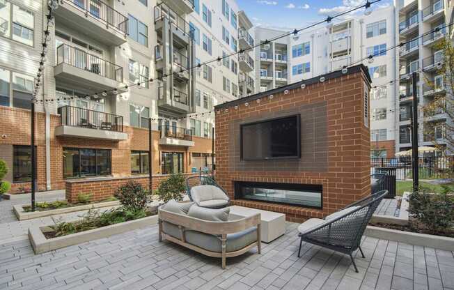an outdoor patio with a fireplace and a couch and a chair at Link Apartments® Calyx, Chapel Hill, 27517