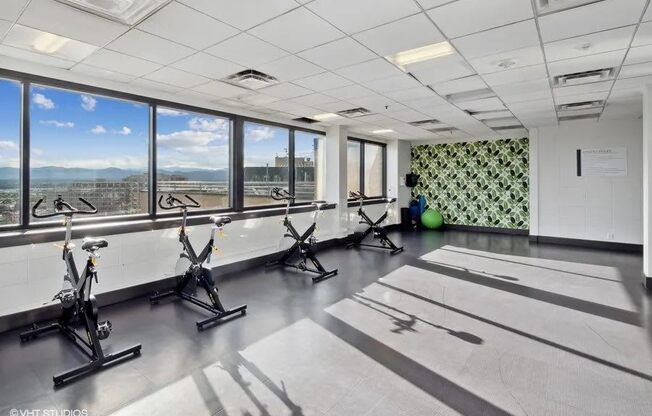 A room with exercise bikes and a green patterned wall at Archer Tower in Denver, CO