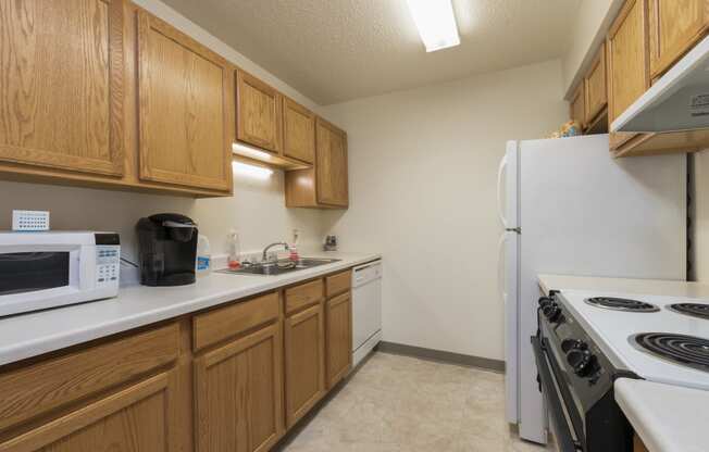 a kitchen with white appliances and wooden cabinets. Bismarck, ND Bradbury Apartments