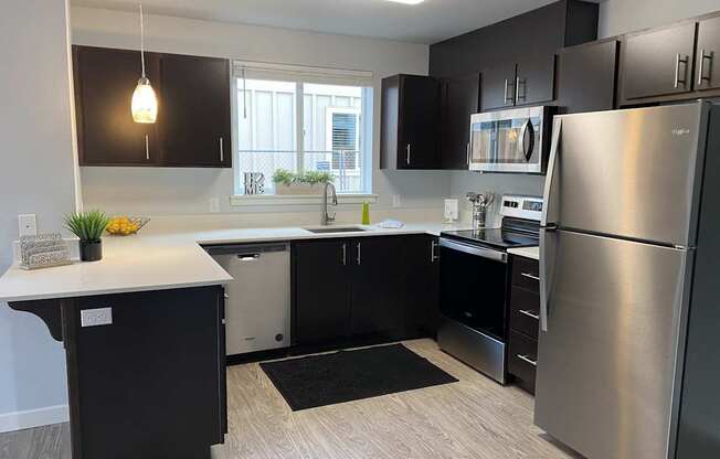 A modern kitchen with black cabinets and stainless steel appliances.