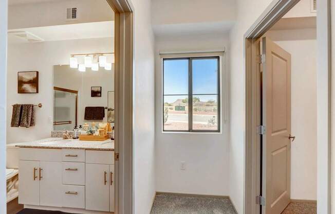 A bathroom with a large mirror and a window overlooking a parking lot.
