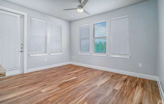 A room with a ceiling fan and wooden flooring.
