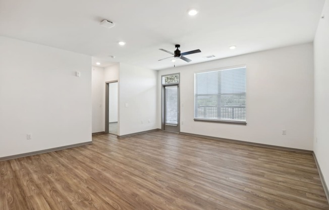 an empty living room with a ceiling fan and a window at The Depot in The Depot Raymore, MO 64083