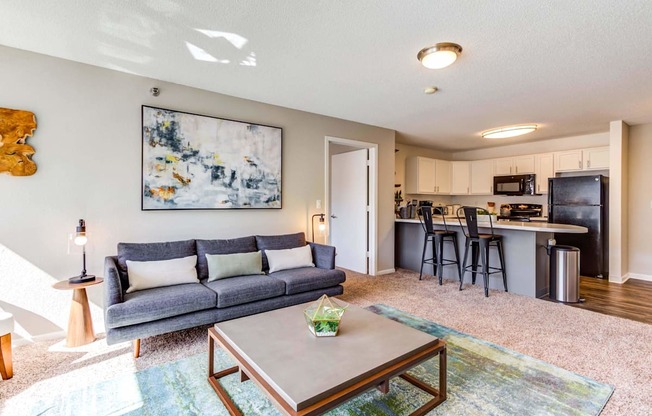 a living room with a couch coffee table and a kitchen in the background