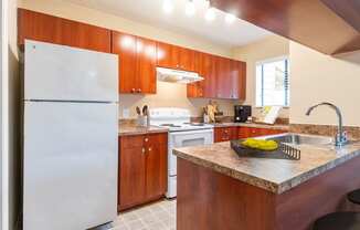A kitchen with a white refrigerator and brown cabinets.