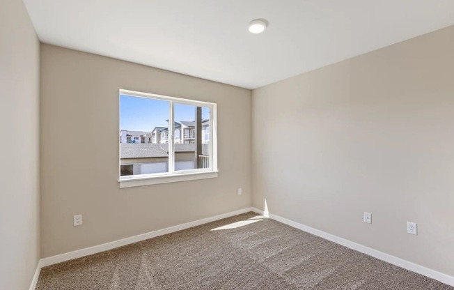 an empty bedroom with a window and carpet