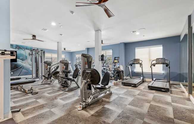 A spacious gym with a variety of equipment including treadmills, elliptical machines, and a rowing machine.