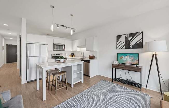 A modern kitchen with white appliances and a dining area with a grey rug.