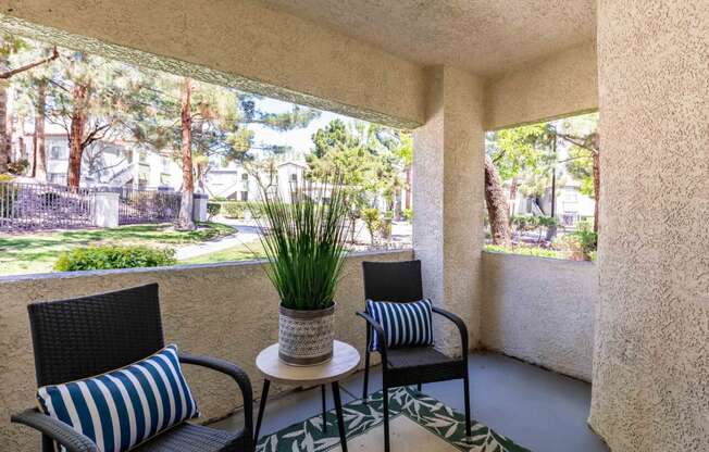 a patio with chairs and a table with a plant on it