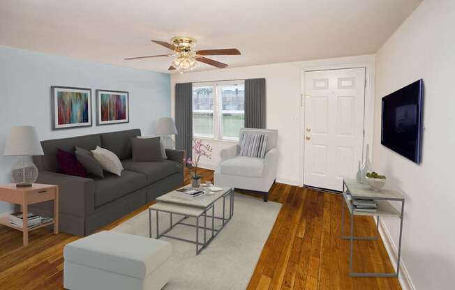 A living room with a grey couch, a coffee table, and a flat screen TV mounted on the wall.
