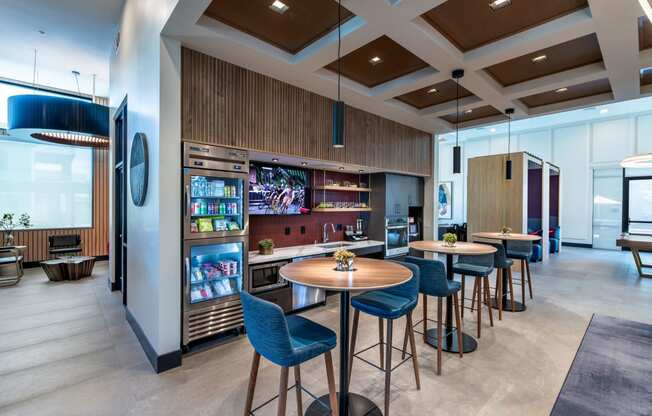 a lobby with tables and chairs and a bar with a television