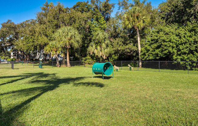 A green tube-like structure sits in a grassy field.