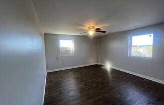 an empty living room with a ceiling fan and a window