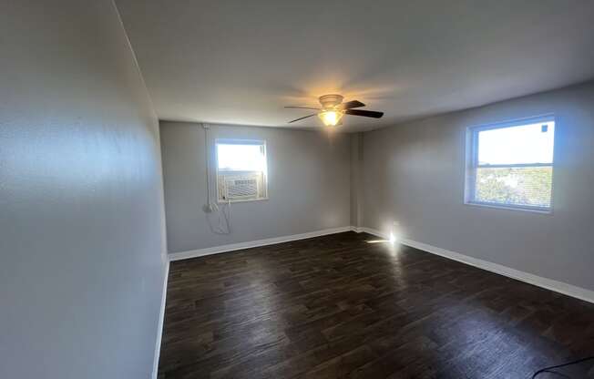 an empty living room with a ceiling fan and a window