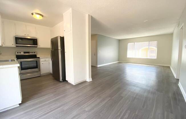 an empty kitchen and living room with a hard wood floor