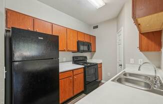 A kitchen with black appliances and wooden cabinets.