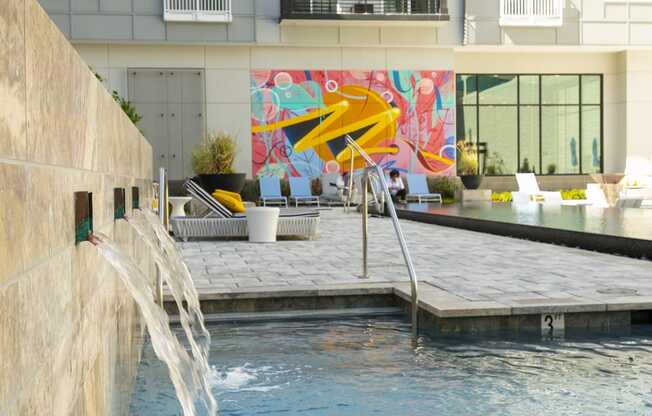 a pool with a waterfall in front of a building