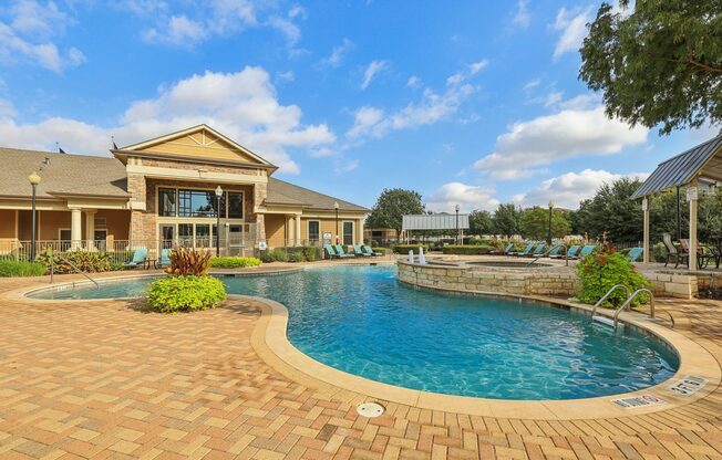 A large outdoor swimming pool surrounded by a brick patio.