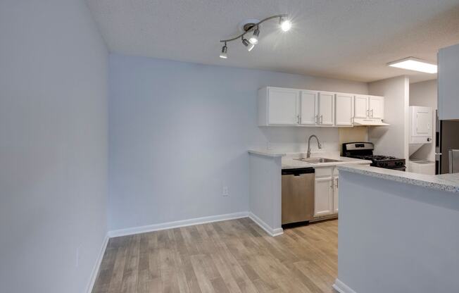 A kitchen area with a sink, stove, and cabinets.
