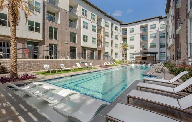 a swimming pool with lounge chairs in front of an apartment building