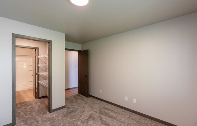 A bedroom with a closet and a door to a bathroom. Fargo, ND Granger Court Apartments.