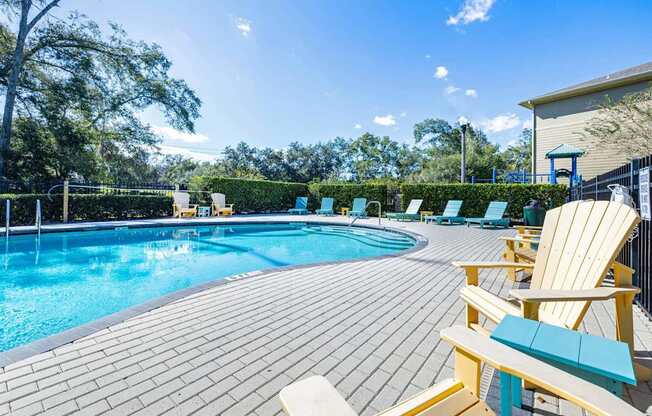 A sunny day at the pool with chairs and a bench.