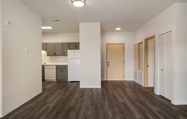 a living room with wood-style flooring, white walls and a kitchen in the background.at Shoreline Village, Washington, 99352