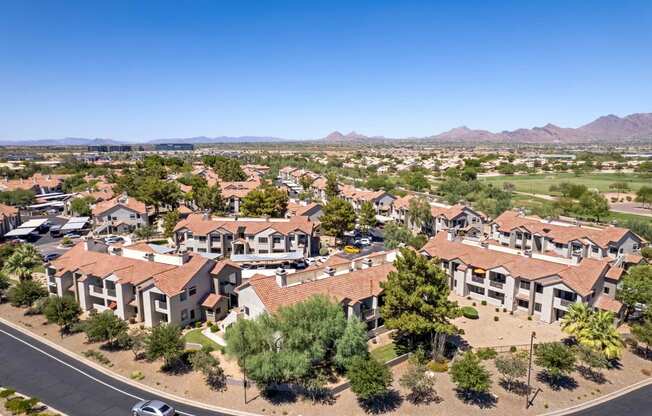 an aerial view of a neighborhood of houses with trees and mountains in the background