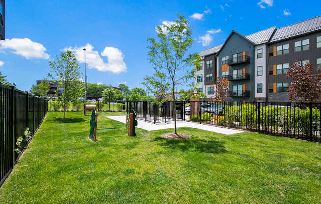 A grassy area with a fence and a building in the background.
