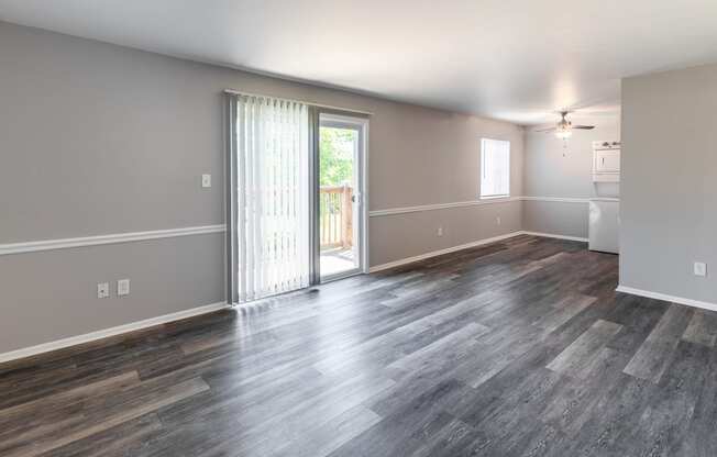 an empty living room with a sliding glass door to a balcony