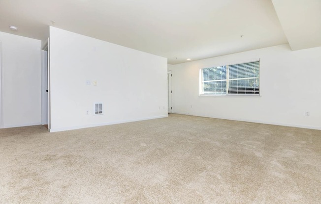 the spacious living room has white walls and carpeting and a window  at Delano, Washington, 98052