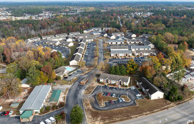 An aerial view of a parking lot and buildings with trees in the background.