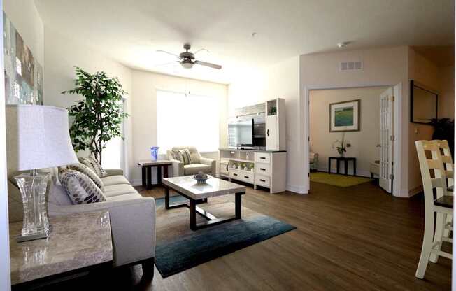 A living room with a couch, a coffee table, and a ceiling fan.