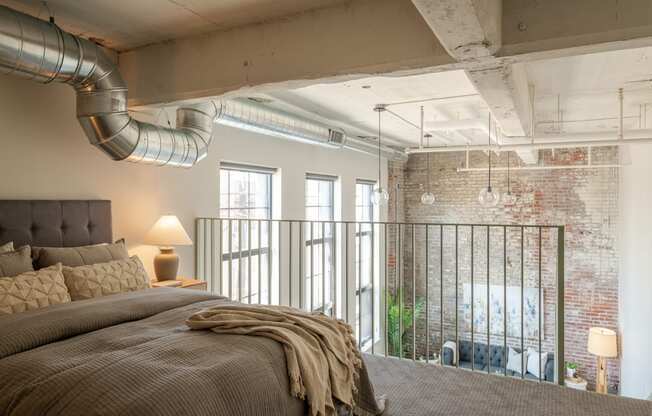 a bedroom with a bed and a exposed brick wall at The 22 Apartments, Missouri