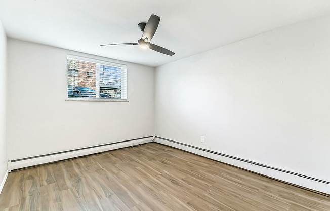 Bright and inviting empty room with sleek wooden floors and a modern ceiling fan, perfect for personalization.
