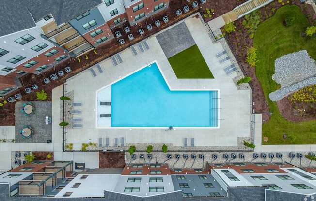 A swimming pool is surrounded by a patio and apartment buildings.