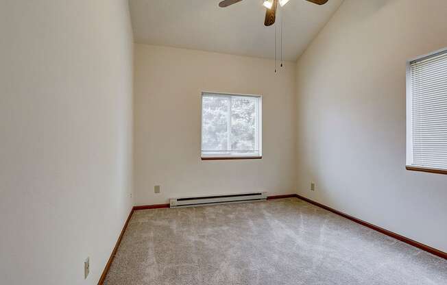 an empty living room with a ceiling fan and a window