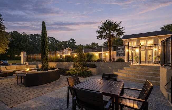 A patio with a table and chairs is lit up at dusk.