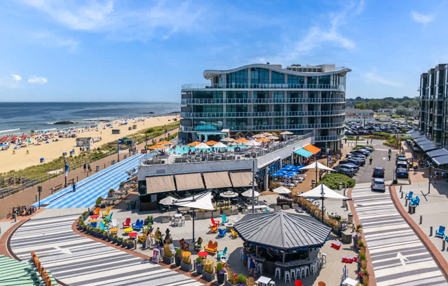 A beachside view with a large building, a gazebo, and people enjoying the sunny day.