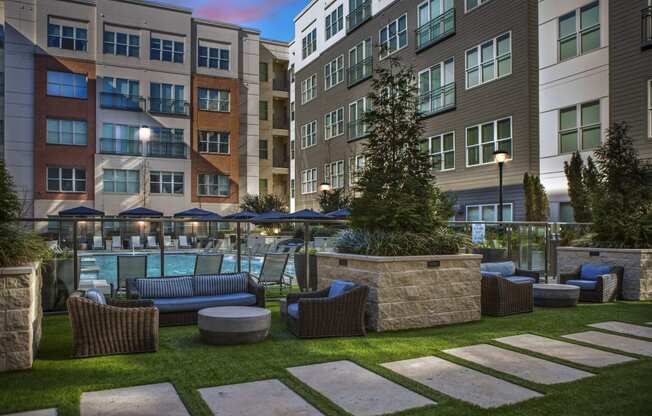 an outdoor lounge area with couches and chairs in front of apartment buildings