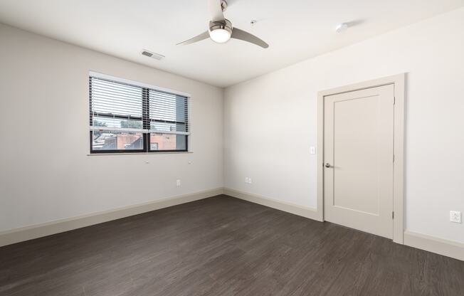 Hibernia bedroom with rich vinyl plank flooring, oversized windows with white blinds and ceiling fan