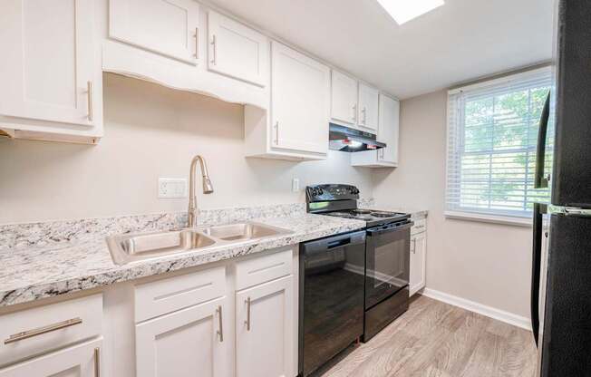 A kitchen with white cabinets and a marble countertop.