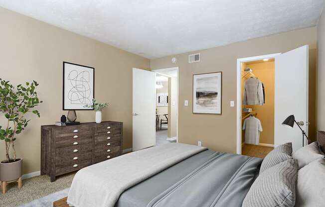 A bedroom with a large bed and a dresser with a plant on top.