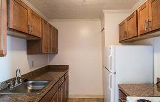 A kitchen with brown cabinets and a white refrigerator at Hummingbird Pointe & The Gardens, Parma, Ohio