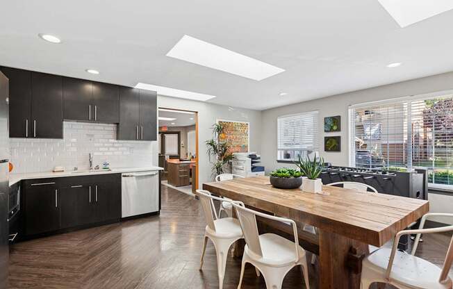 A modern kitchen with a wooden table and white chairs.