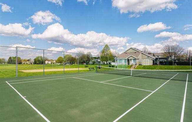a tennis court with a house in the background