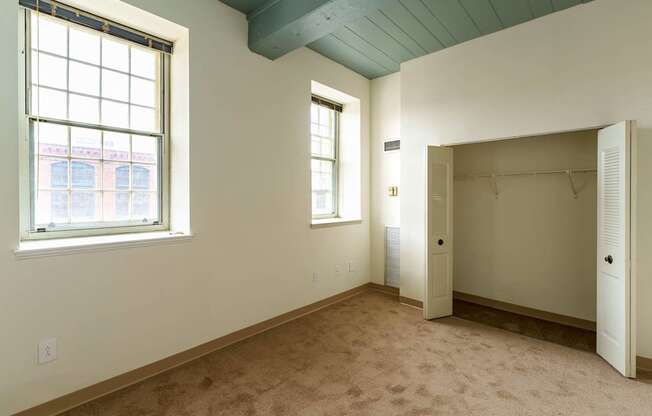 A room with a carpeted floor, a window, and a closet.