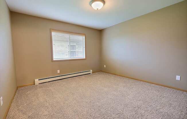 a bedroom with carpet and a window. Fargo, ND Urban Plains Apartments