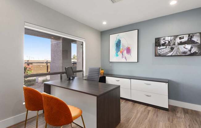 A room with a desk, chairs and pictures on the wall.