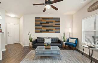 A living room with a black couch and a wooden wall hanging.